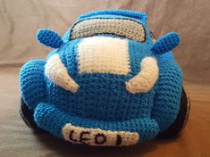 a crocheted blue toy car sitting on top of a wooden table