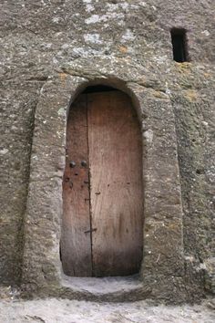 an old wooden door in the side of a stone building with two small round windows