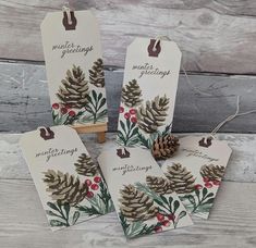 four christmas gift tags with pine cones and berries