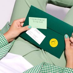 a woman holding a green envelope with a smiley face on it and a note attached to the envelope