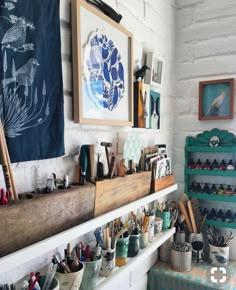 a room filled with lots of art and craft supplies on shelves next to a white brick wall