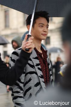 a man holding an umbrella while standing on the street in front of other people and buildings