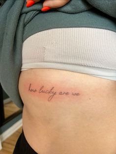 a woman's stomach with the words how lucky are we tattooed on her belly