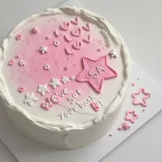 a white cake with pink frosting and stars on it