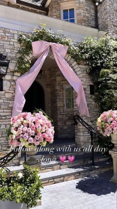 the entrance to a building with pink flowers on it's front door and an arch that says, now long with us all day