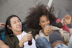 two people sitting on a couch with drinks