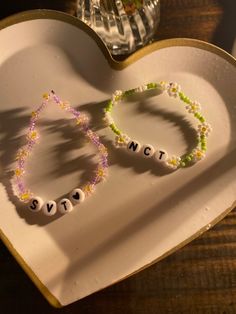 two beaded bracelets sitting on top of a heart shaped tray