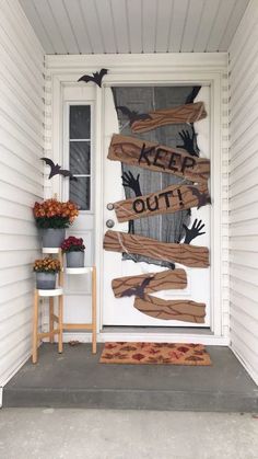 a door decorated with halloween decorations and words that say keep out on the front porch