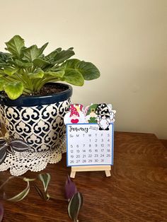 a potted plant sitting on top of a wooden table next to a calendar and card