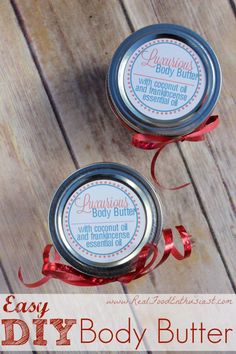 two homemade body butters sitting on top of a wooden table with red ribbon around them