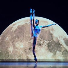 a woman in blue is dancing on stage with the moon behind her