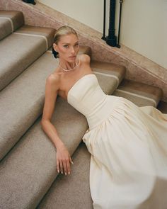 a woman in a white dress is laying on the stairs with her hand on her hip