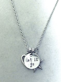 a silver necklace with the words let it go written on it and an arrow charm