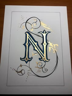 the letter n is made up of gold and black letters with swirly designs on white paper