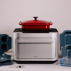 a red pot sitting on top of a toaster oven next to other kitchen items