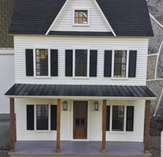 a model house with black shutters and white siding