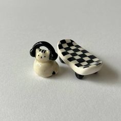 two small ceramic figurines sitting next to each other on a white table top