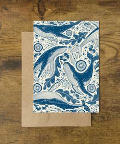 a card with blue and white ink on it, depicting two dolphins swimming in the ocean