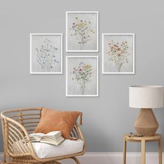 a living room with four framed pictures on the wall and a wicker chair next to it