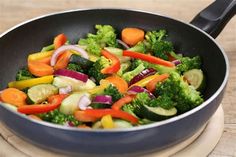 a pan filled with vegetables on top of a wooden table