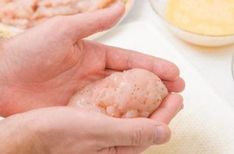 a person holding something in their hand near other plates and bowls on the table with food