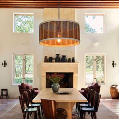 a dining room table with chairs and a fire place in the center surrounded by windows