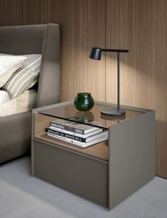 a nightstand with books on it next to a bed