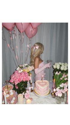 a barbie doll standing in front of a cake with pink flowers and candles on it