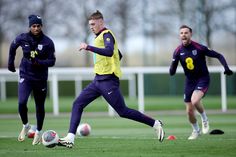 two soccer players are running with the ball in front of them and one is wearing a yellow jacket