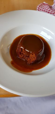 a small piece of cake covered in sauce on a white plate