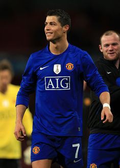 a man in blue soccer uniform standing next to another man wearing black and yellow shirts