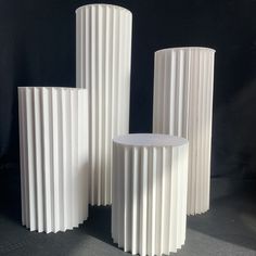 three tall white vases sitting next to each other on a table in front of a black background