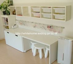 a white desk with two stools next to it and some shelves on the wall