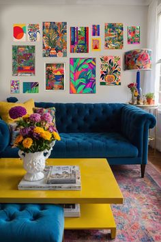 a living room with blue couches and colorful paintings on the wall behind it,