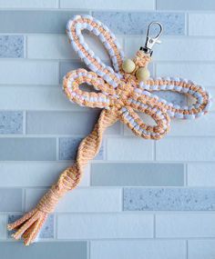 an orange and white dragon keychain hanging from a hook on a tile wall