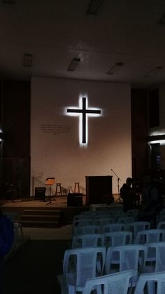 an empty church with white chairs and a cross on the wall