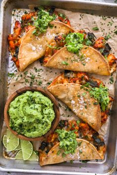 tortillas and guacamole on a baking sheet with lime wedges