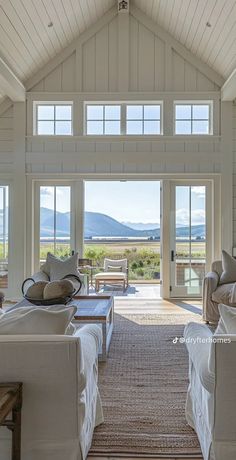 a living room filled with white furniture and large open doors to an outside patio area