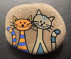 a painted rock with two cats on it