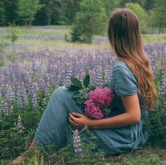 a woman sitting on the ground with flowers in her lap