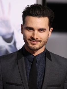 a man in a suit and tie smiling at the camera