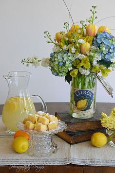 a vase filled with flowers and lemons on top of a table next to books