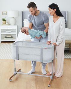 a man and woman standing next to a baby in a crib