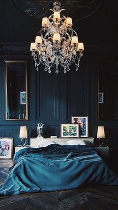 a chandelier hangs from the ceiling above a bed in a room with blue walls