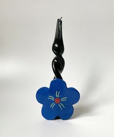 a blue flower shaped object sitting on top of a white table next to a black hook