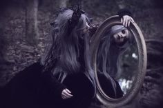 a woman with long hair standing in front of a mirror