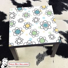 a small table with an abstract design on it's top, sitting on a black and white rug