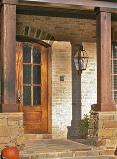 the front porch is decorated with pumpkins and an old fashioned lantern on it's post