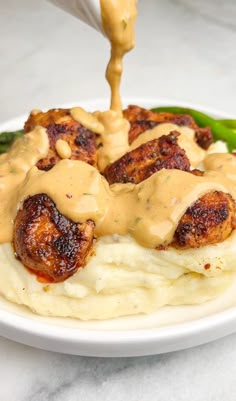 a plate with mashed potatoes covered in gravy and green asparagus