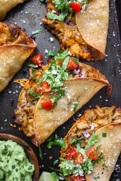 several tortillas on a tray with guacamole and salsa